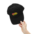 A hand holds a black Meu Meu & Croc Tropical Store distressed baseball cap with a colorful tropical logo.