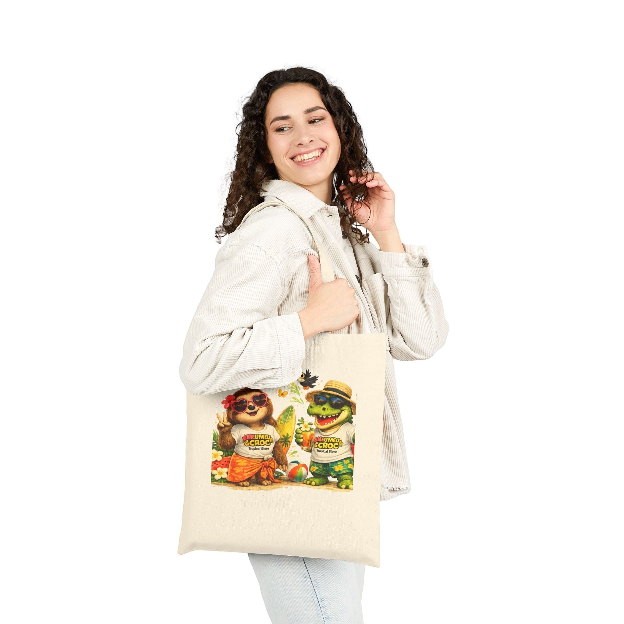 Woman wearing a Meu Meu & Croc Tropical Store natural cotton canvas tote with a sloth and crocodile beach graphic.