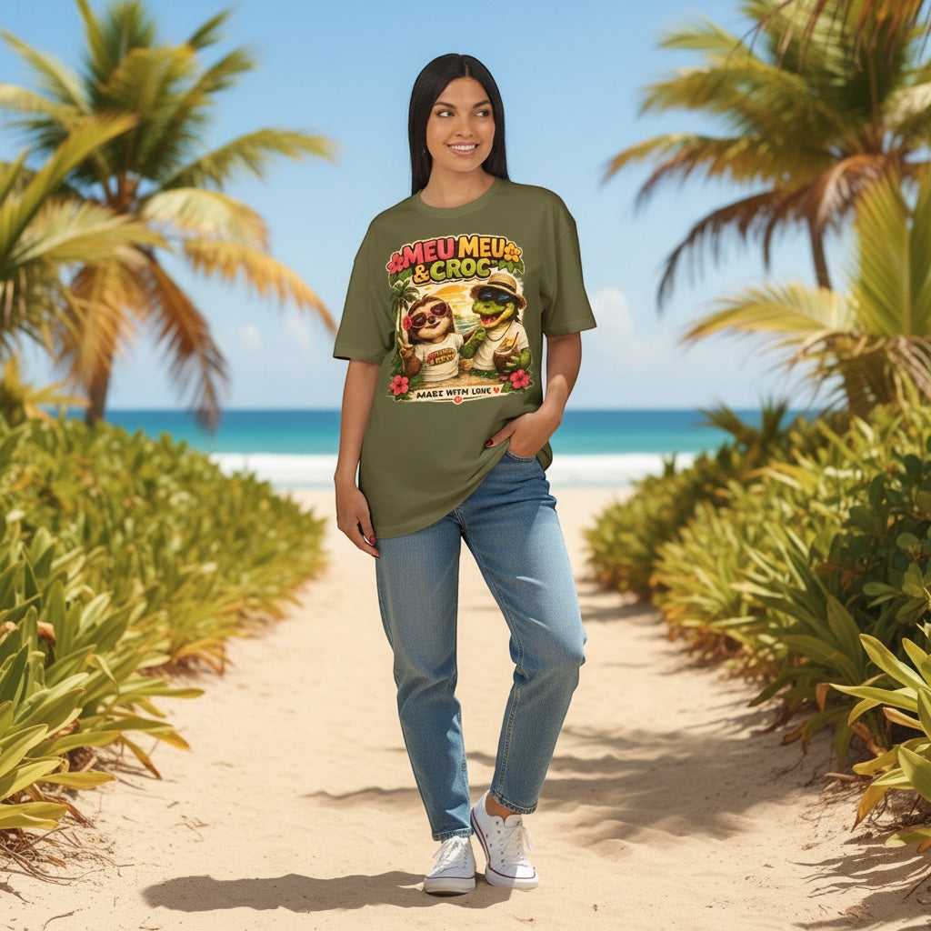 Woman wearing an olive green Meu Meu & Croc Tropical Store graphic tee with a sloth and crocodile print on a beach.